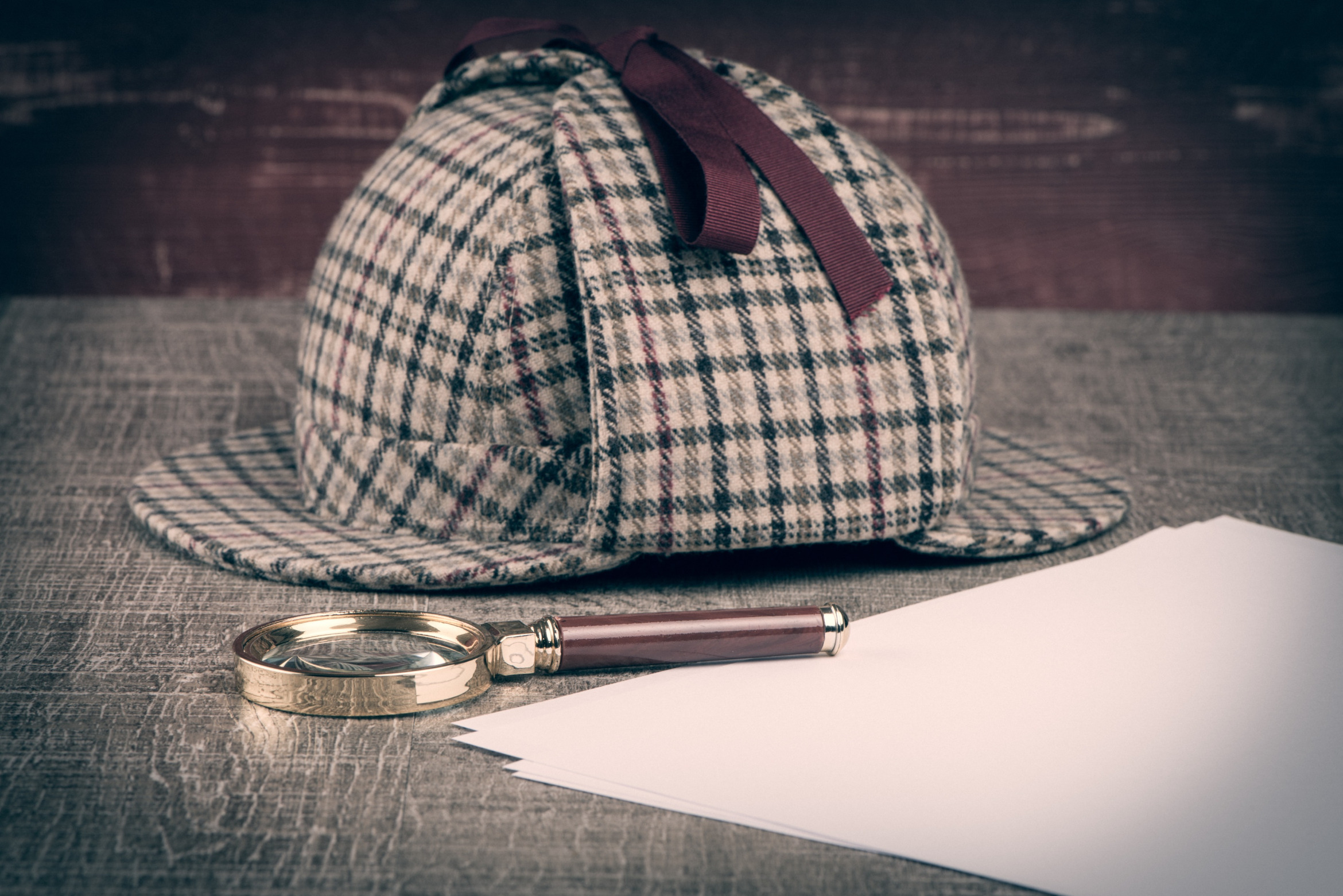 Sherlock-Holmes-Deerstalker, Lupe und Papier auf Tisch; Privatermittler Bülach (Kanton Zürich), Detektivagentur Bülach (Kanton Zürich), Detektivteam Bülach (Kanton Zürich), Detektei-Service Bülach (Kanton Zürich)